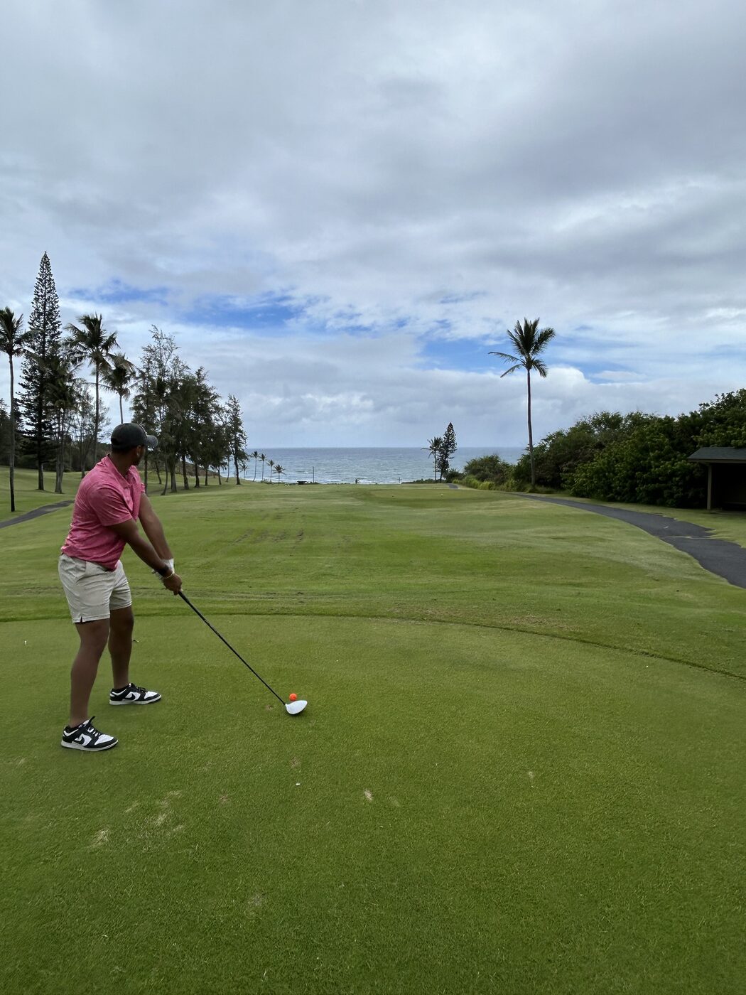 Akshat mid golf swing on a coastal course.